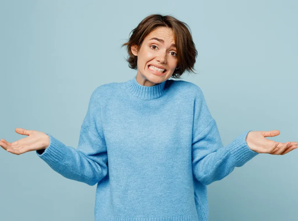 White woman in blue shirt shrug her arms and shoulders