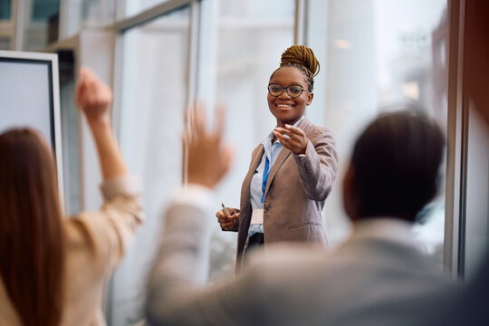 Happy black business woman speaking to a group of people in a room