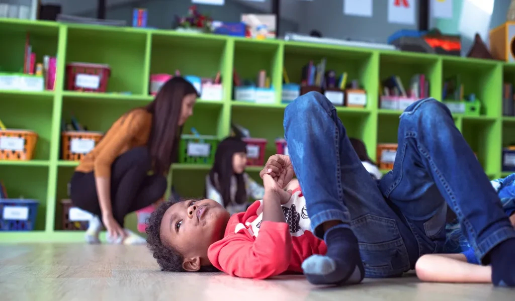 Young black child lying on the floor at school