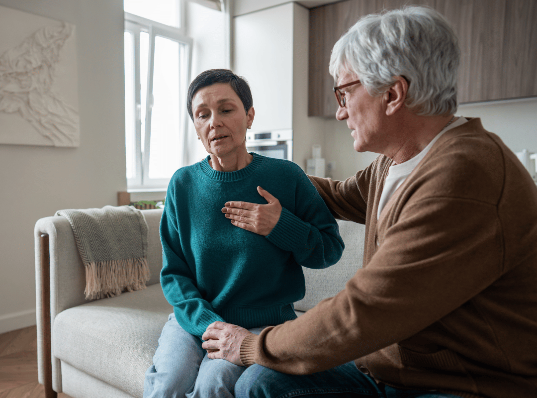 elderly man sitting next to a woman in distress