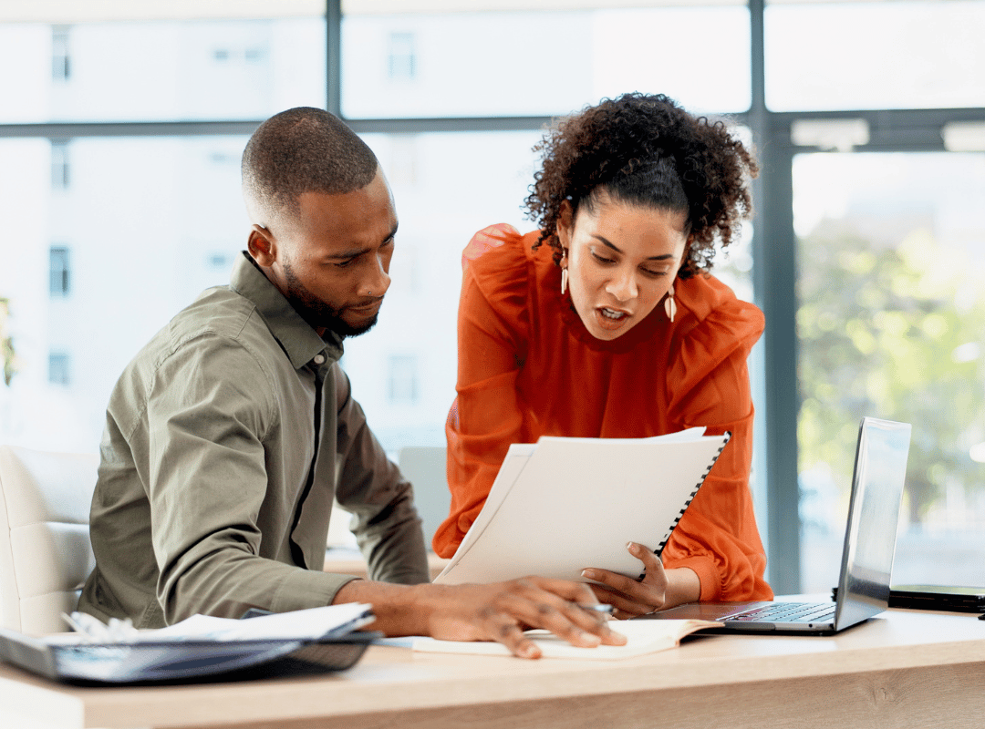 A man and woman at a desk reviewing papers.